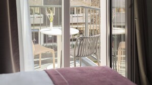 A hotel room with a balcony, a bed with a pink blanket, and a view of the outdoor seating area. - Garner Hotel Berlin - Wilmersdorf by IHG (Berlin)
