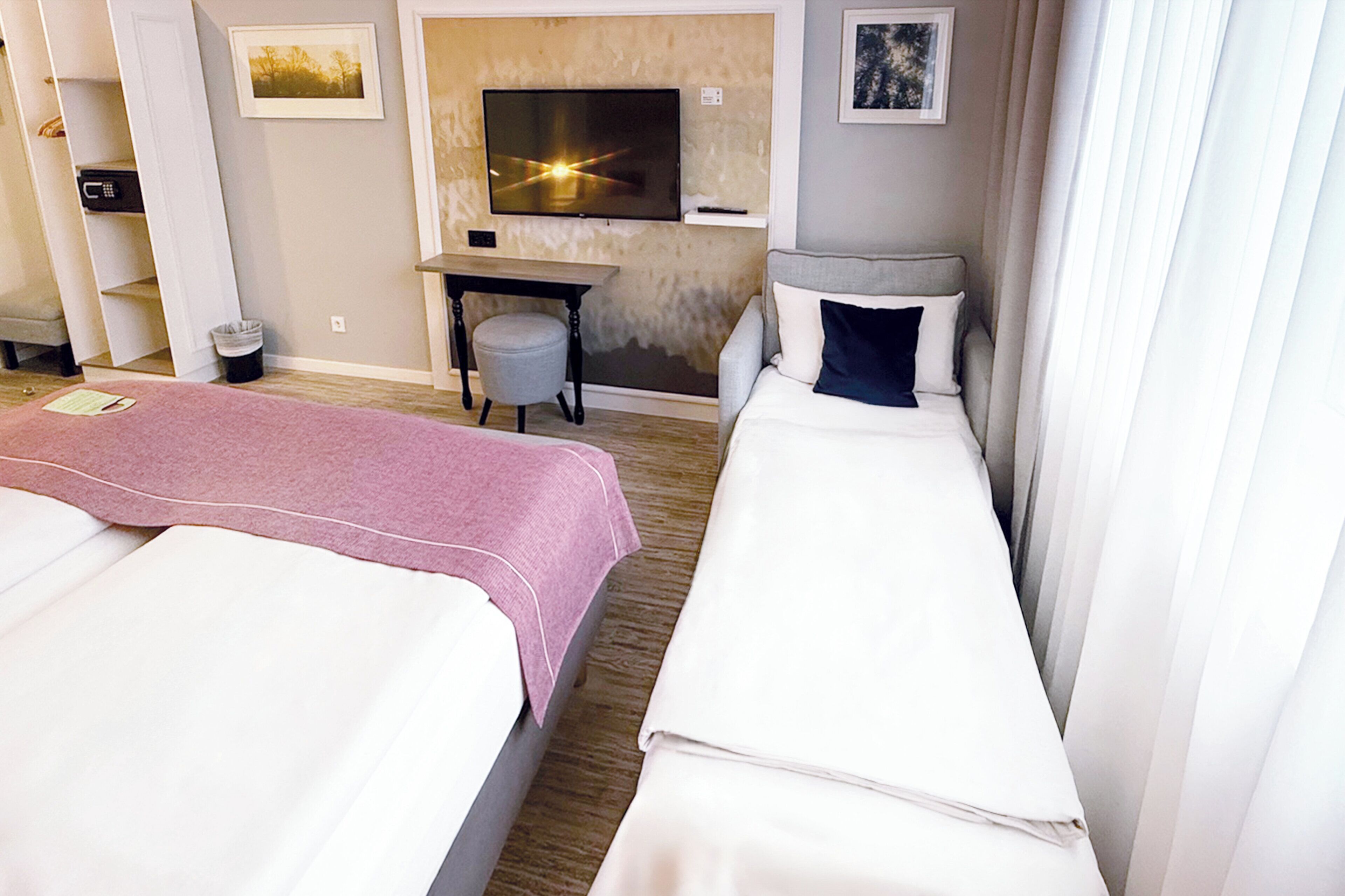Een hotelkamer met twee bedden, een bureau, een televisie en een zithoekje.