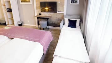 Een hotelkamer met twee bedden, een bureau, een televisie en een zithoekje.