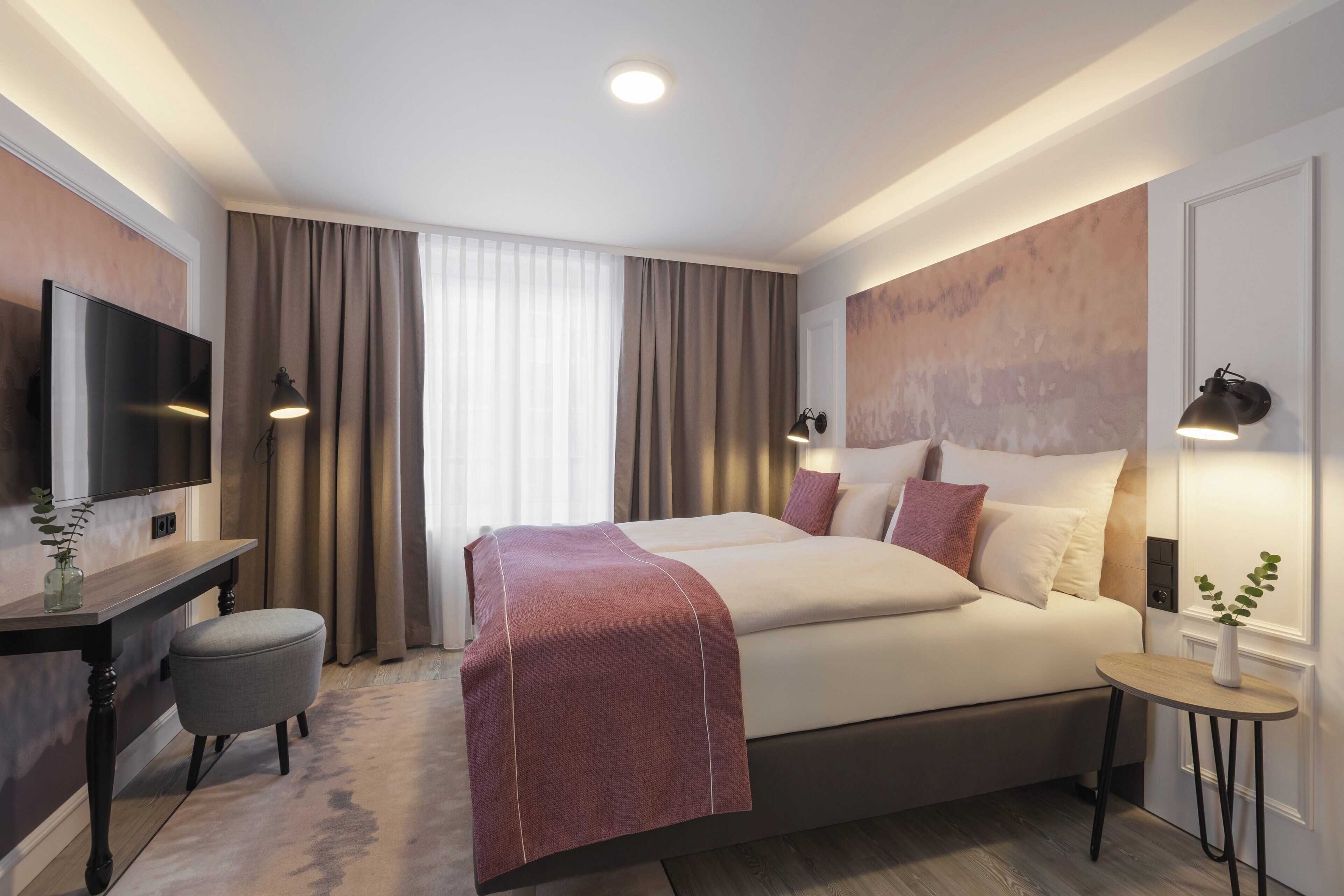 Een moderne hotelkamer met een groot bed, een bureau en een televisie.