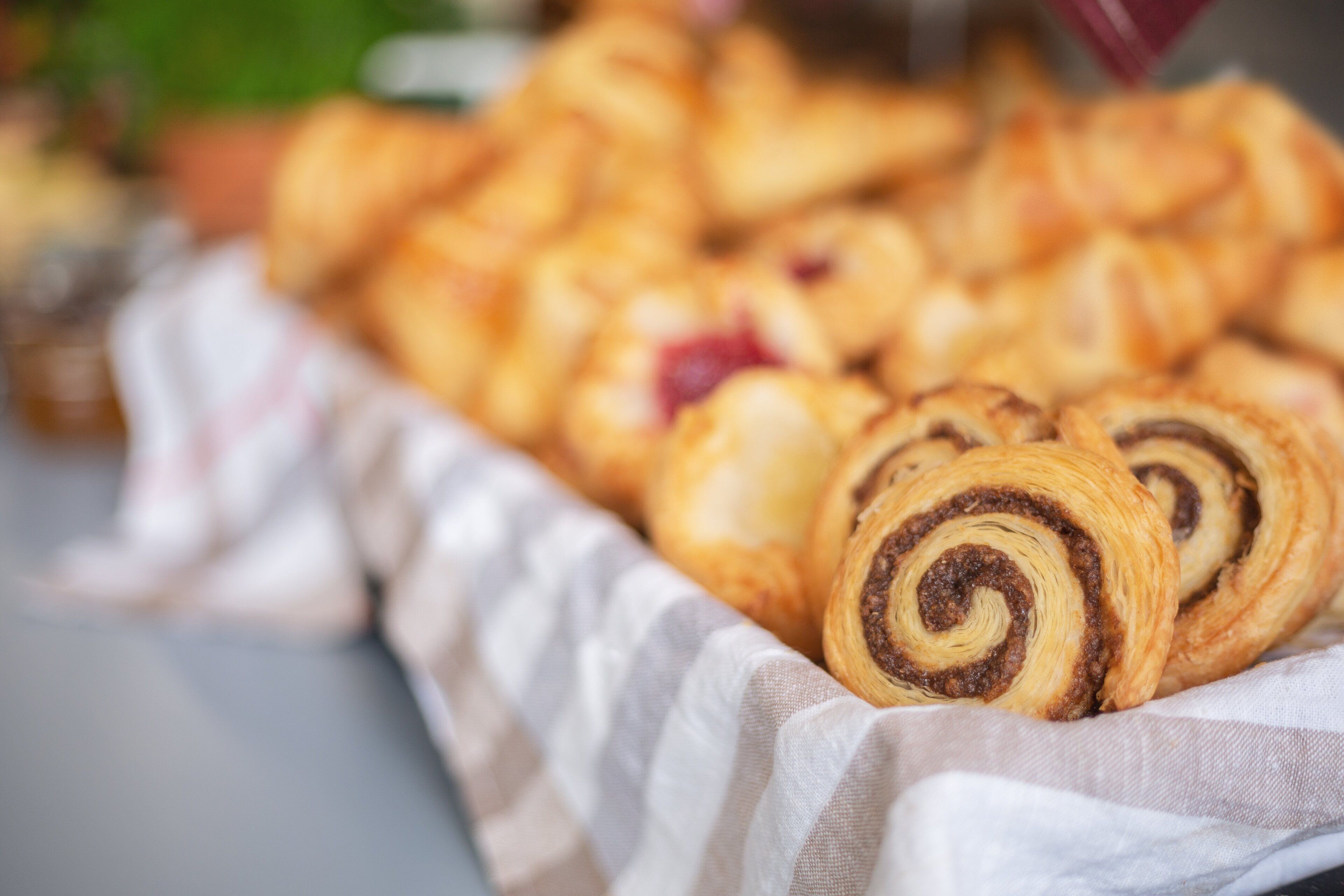 A tray of assorted pastries, including chocolate swirled and fruit-filled varieties, arranged on a cloth.