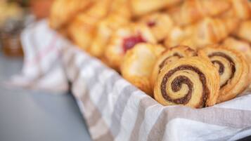 A tray of assorted pastries, including chocolate swirled and fruit-filled varieties, arranged on a cloth.