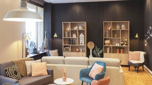 A modern living room with a sectional sofa, a blue armchair, and two wooden shelving units with decorative items.