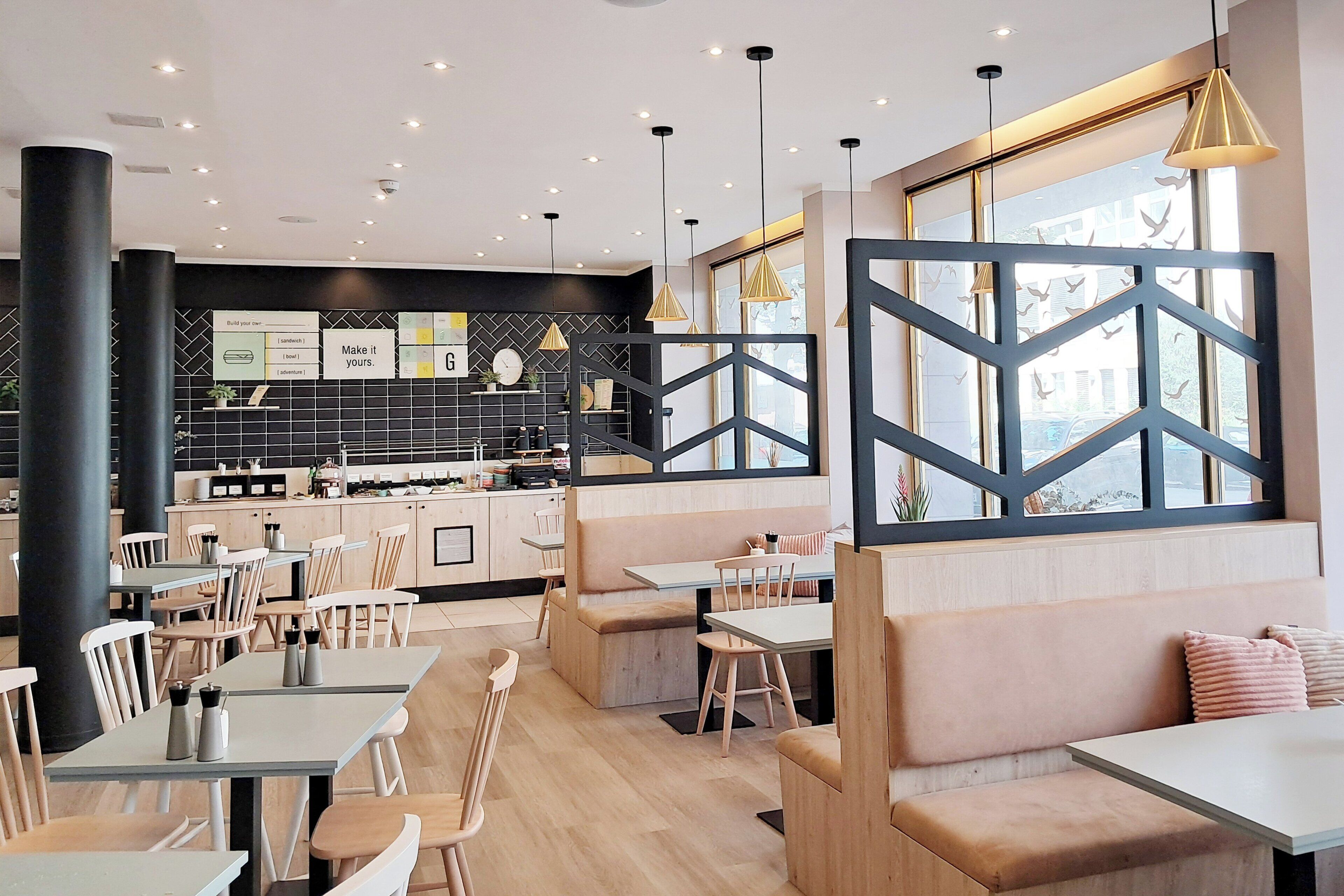 Un restaurante moderno con mobiliario de madera, decoración blanco y negro y amplios ventanales.
