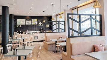 Un restaurante moderno con mobiliario de madera, decoración blanco y negro y amplios ventanales.