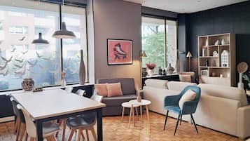 Un salon moderne avec un coin repas, de grandes fenêtres et une bibliothèque.