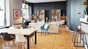 A modern living room with a dining area, a sofa set, and a kitchen counter with stools.