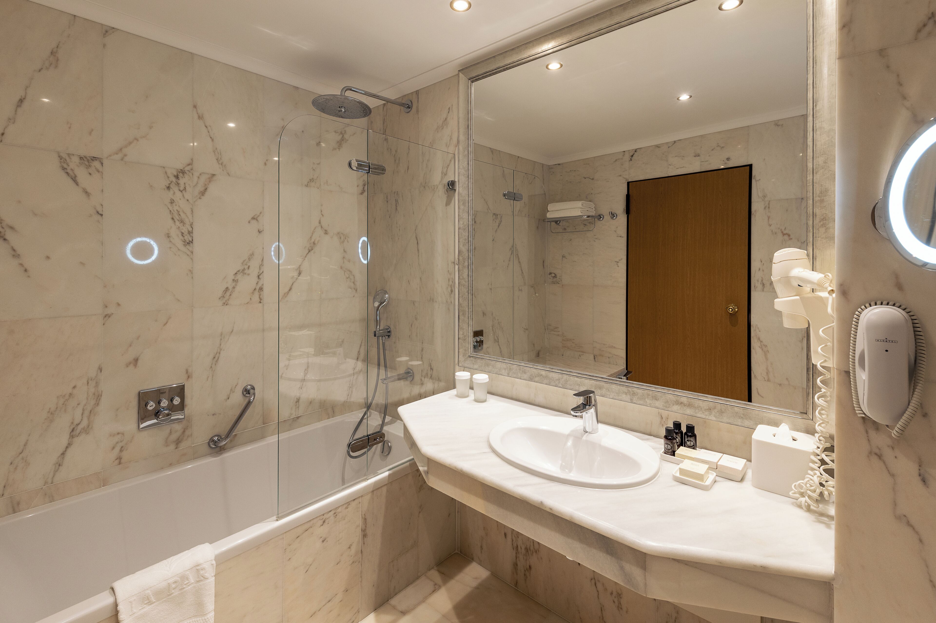 A modern bathroom with a glass-enclosed shower, a white sink, and a large mirror.