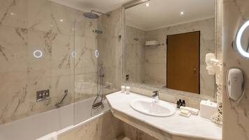 A modern bathroom with a glass-enclosed shower, a white sink, and a large mirror.