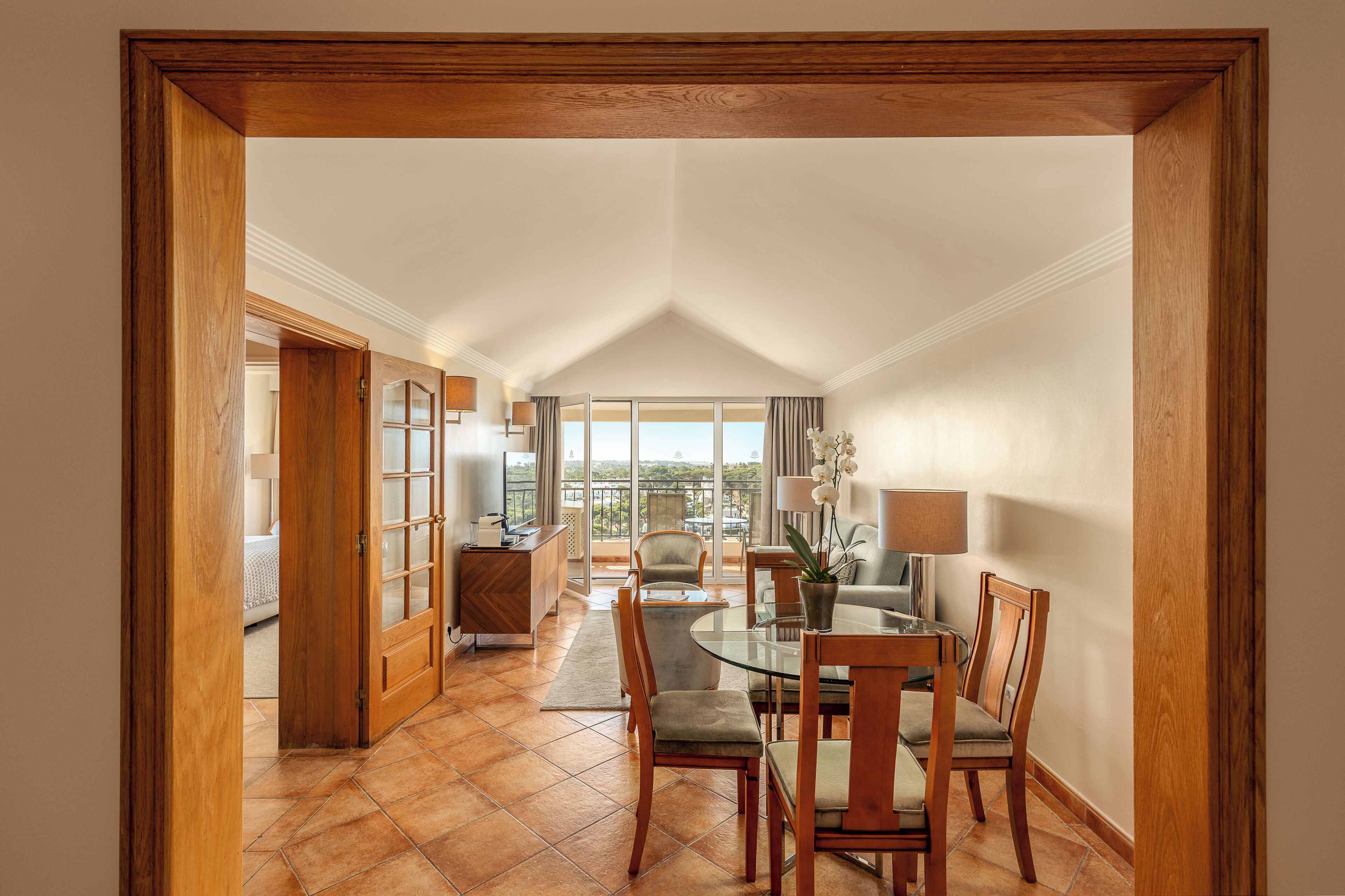 Un espace repas avec une table en verre, des chaises en bois et une vue sur l’extérieur.