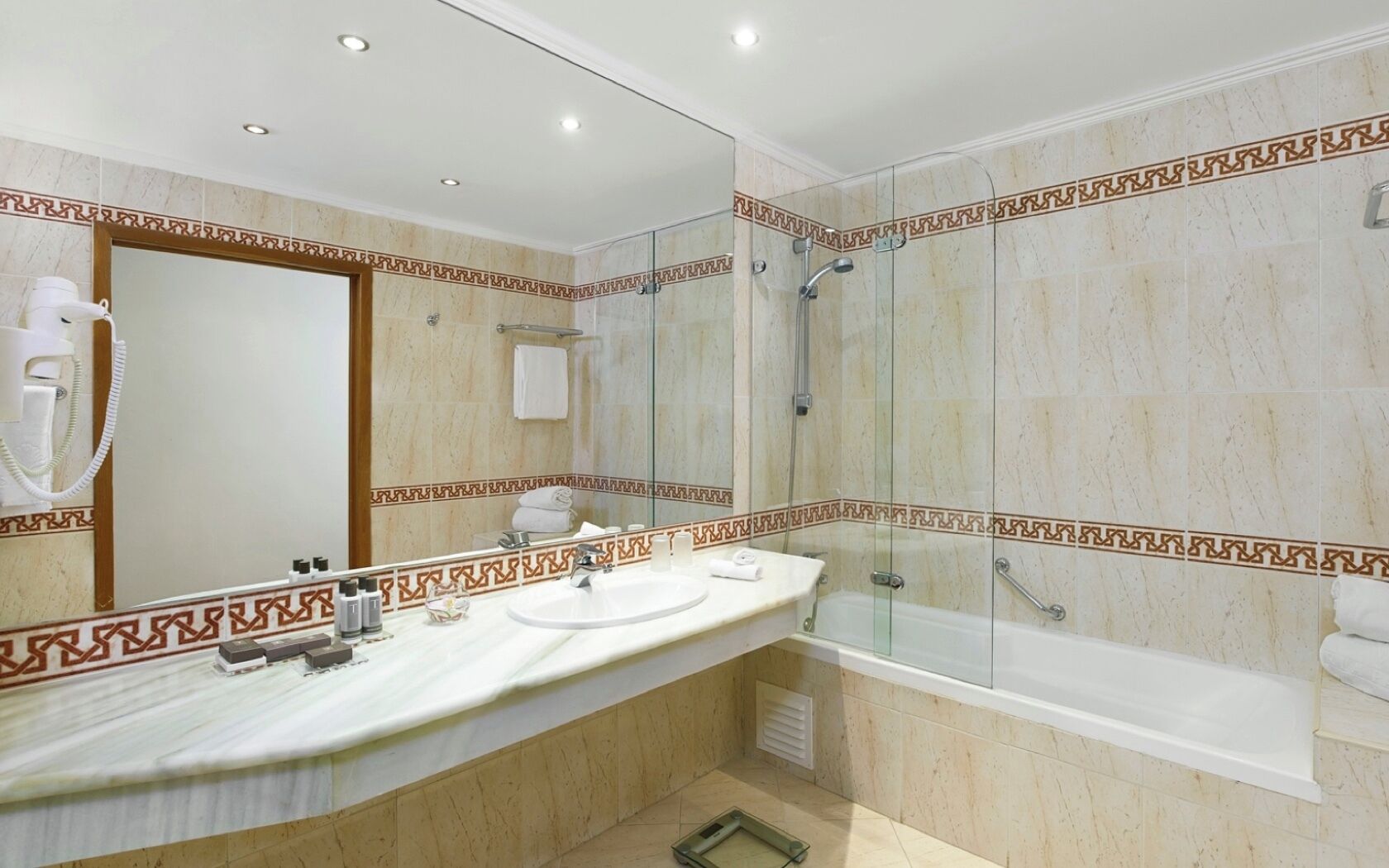 Un baño con tocador de mármol, ducha con cerramiento de vidrio y bañera.