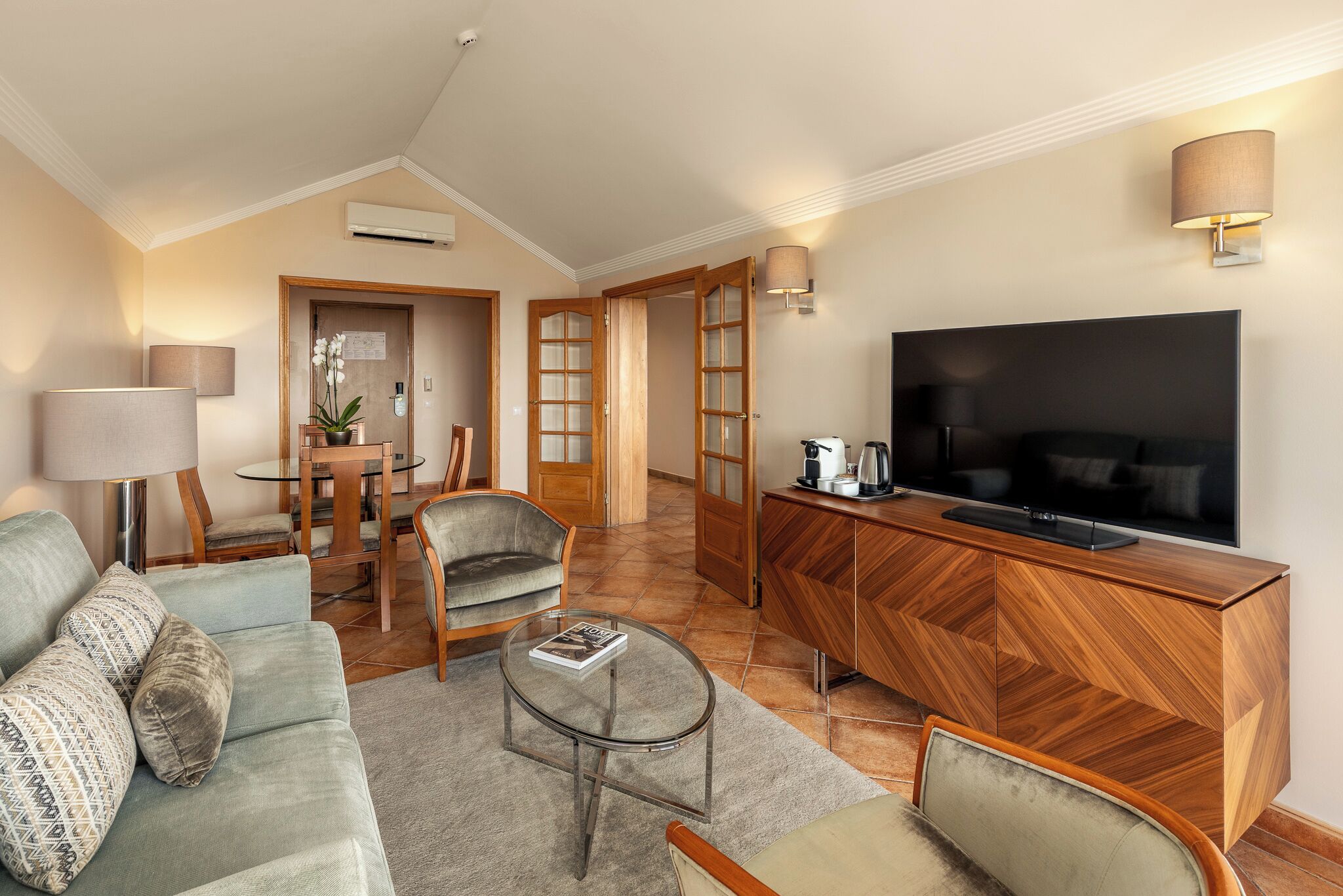 A modern living room with a sofa, chairs, a coffee table, a TV, and a wooden cabinet.