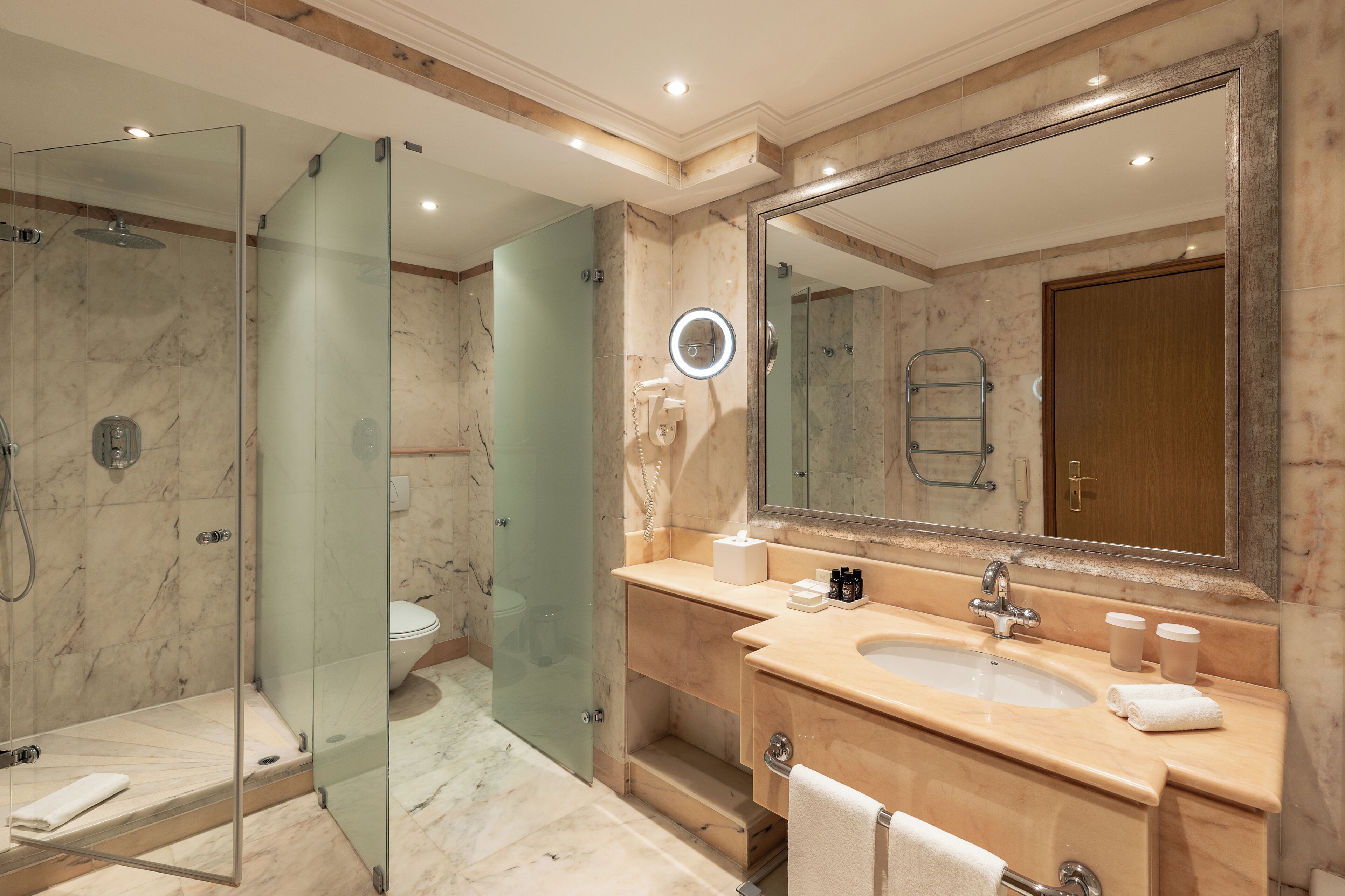 Un bagno moderno con doccia vetrata, un ampio specchio e un mobile lavabo con lavandino e porta asciugamani.