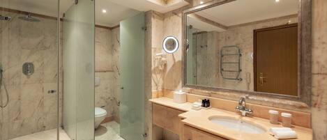 A modern bathroom with a glass-enclosed shower, a large mirror, and a vanity with a sink and towel rack.