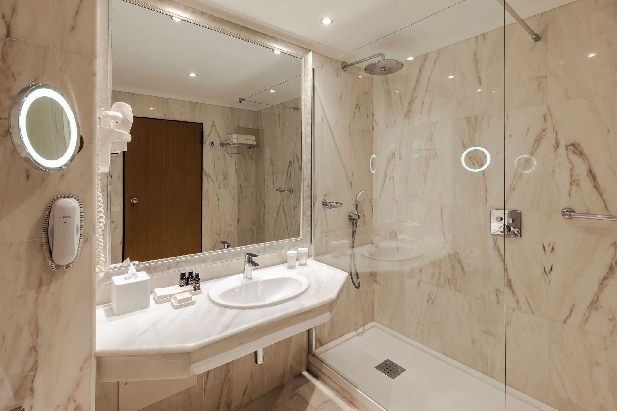 A modern bathroom with a large mirror, a sink, and a shower.