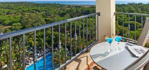 A balcony with a view of a lush landscape and a pool.