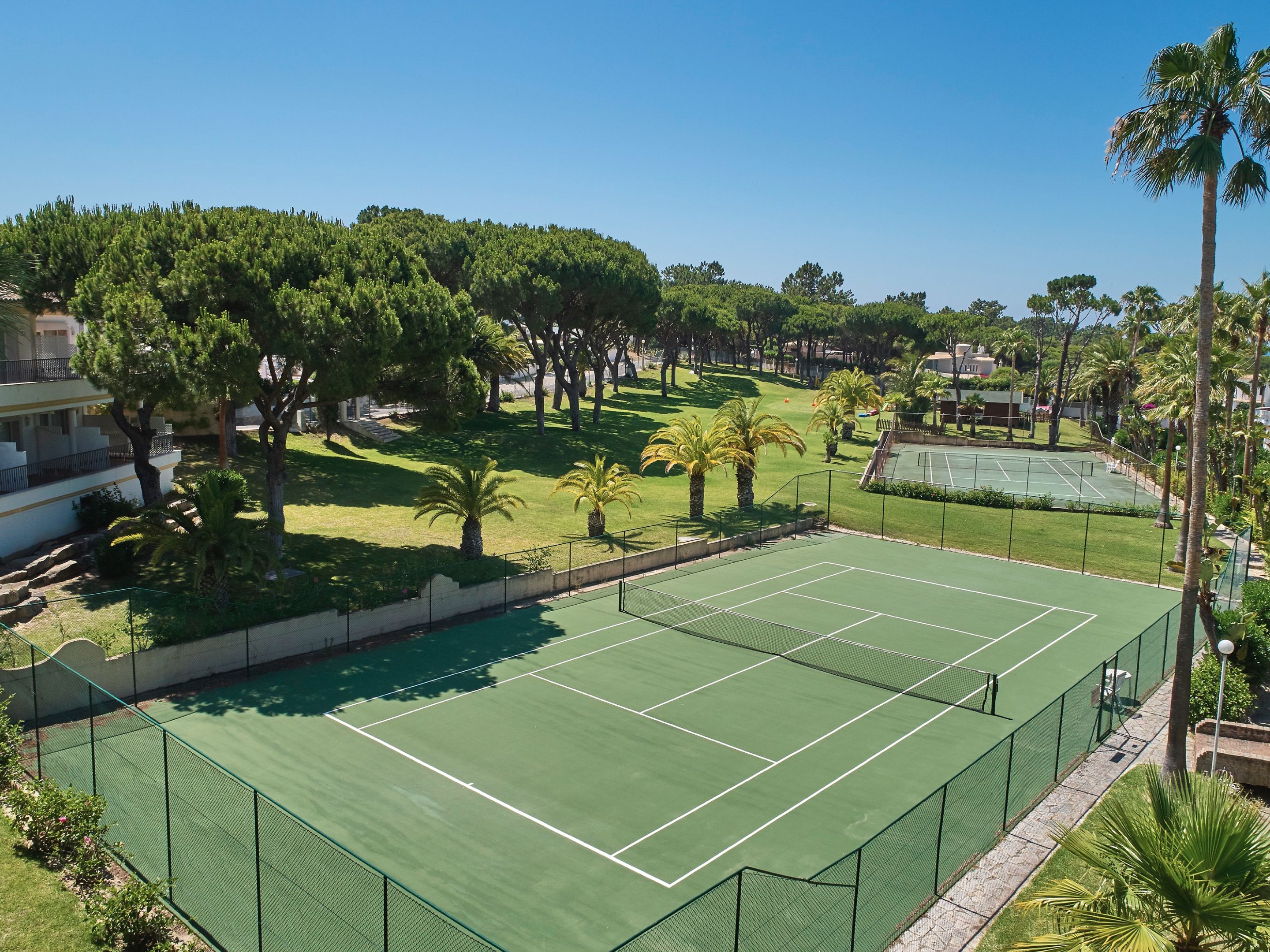Ein Tennisplatz, umgeben von Bäumen und einem Gebäude.