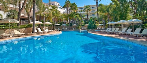 Alberca al aire libre, sombrillas en la alberca y camastros