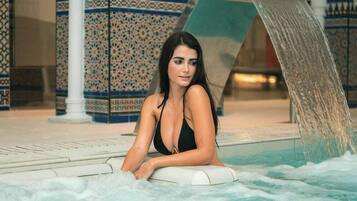 A person relaxing in a hot tub with a decorative fountain in the background.