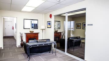 A conference room with a table, chairs, a fireplace, and a large mirror.