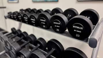 Um suporte com halteres pretos, identificados como 'FITMAX BY UMAX', com pesos marcados '20'.