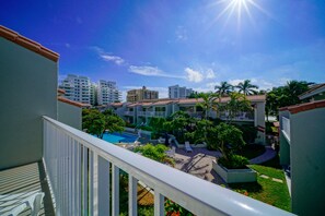 A hotel courtyard with a swimming pool, palm trees, and a view of surrounding buildings. - Ventura at Boca Raton (Boca Raton)