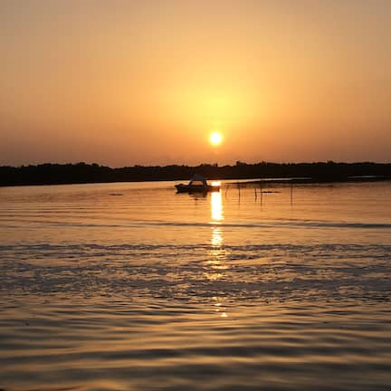 A sunset over a calm body of water with a boat in the distance.