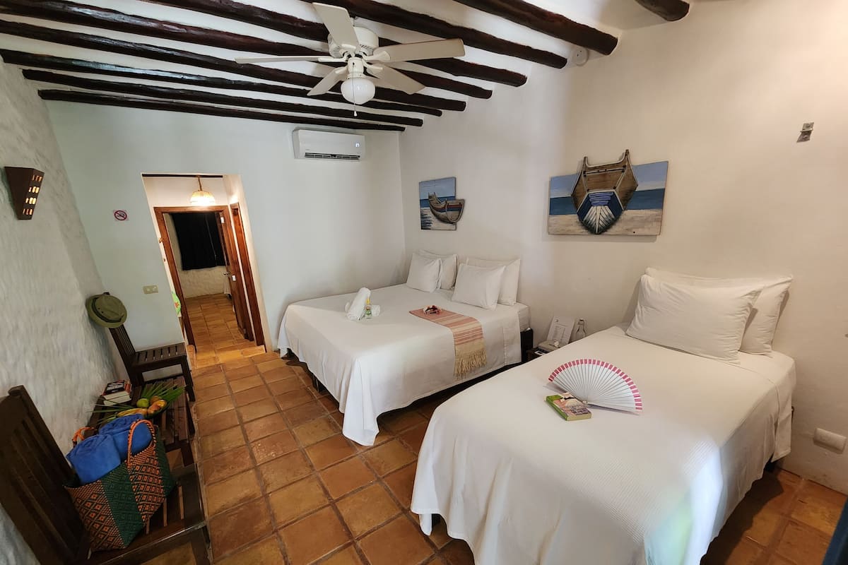 A room with two single beds, a ceiling fan, and a painting on the wall.