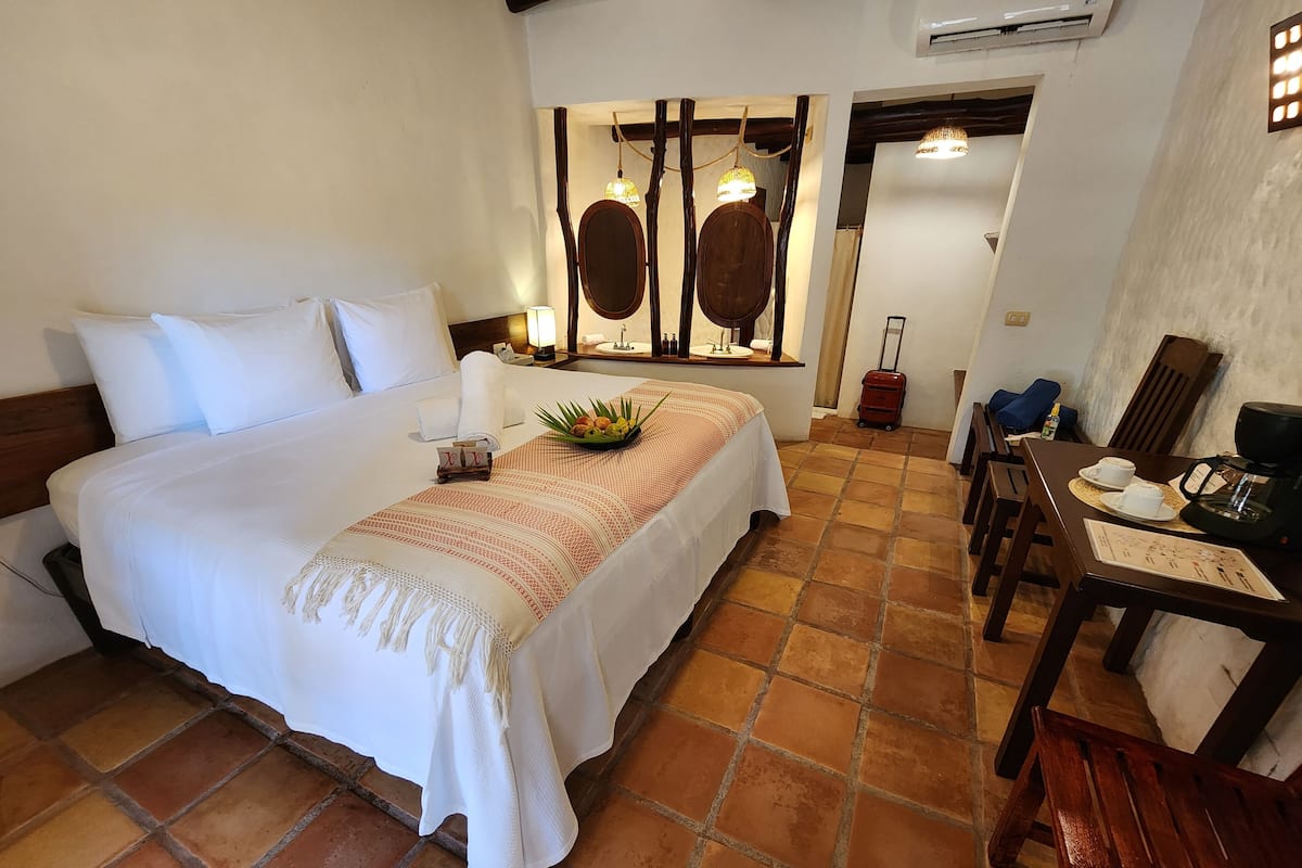 A well-appointed hotel room with a large bed, a dining area with a table and chairs, and a small kitchenette.