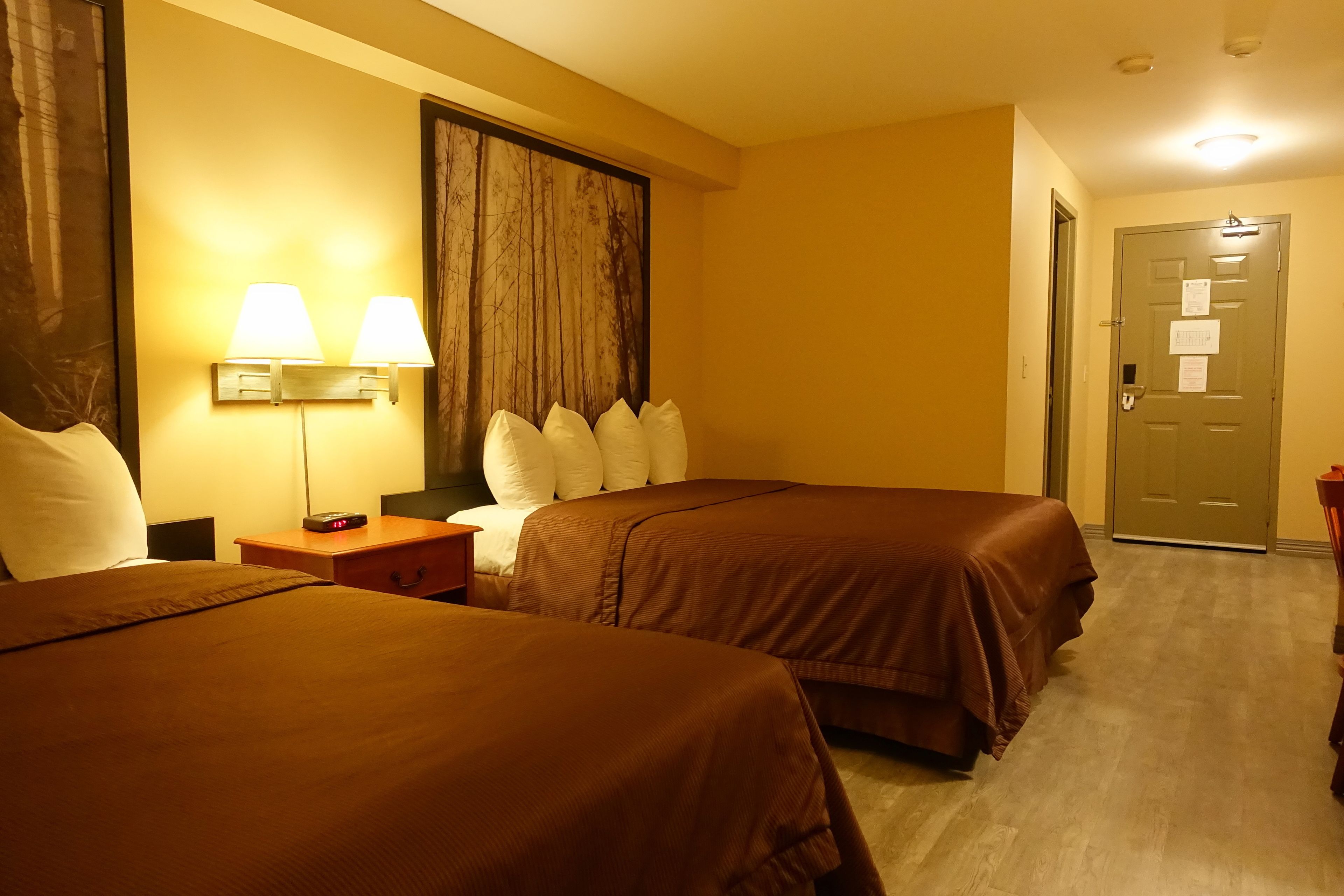 Une chambre d’hôtel avec deux lits, une table de chevet, une lampe et une porte à clé.