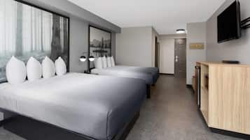 Una habitación de hotel moderna con dos camas, un ventanal con vistas a un bosque, un televisor de pantalla plana y una mesita de noche de madera.