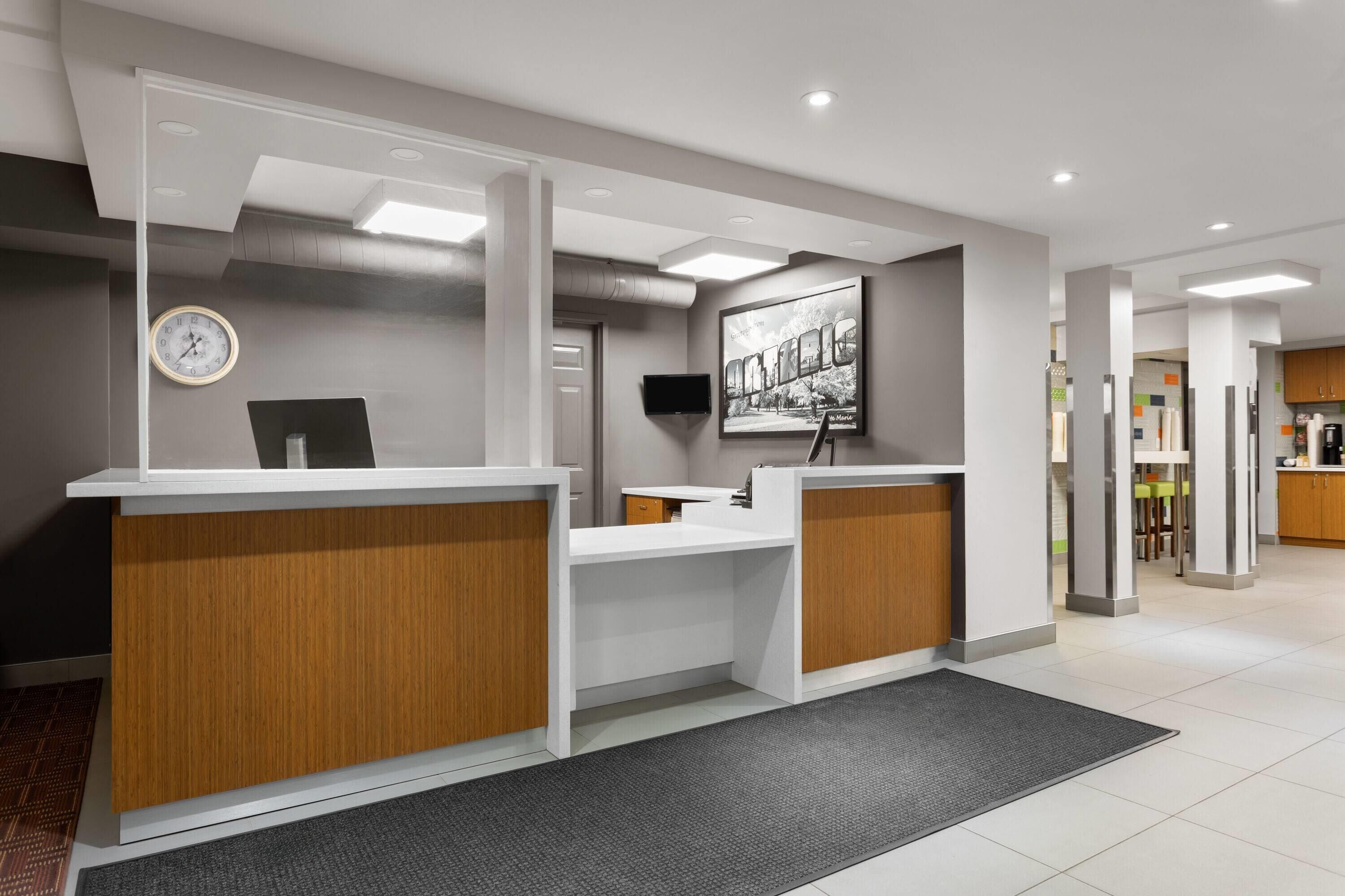 A reception area with a reception desk, a clock, a flat-screen TV, and a framed picture on the wall.