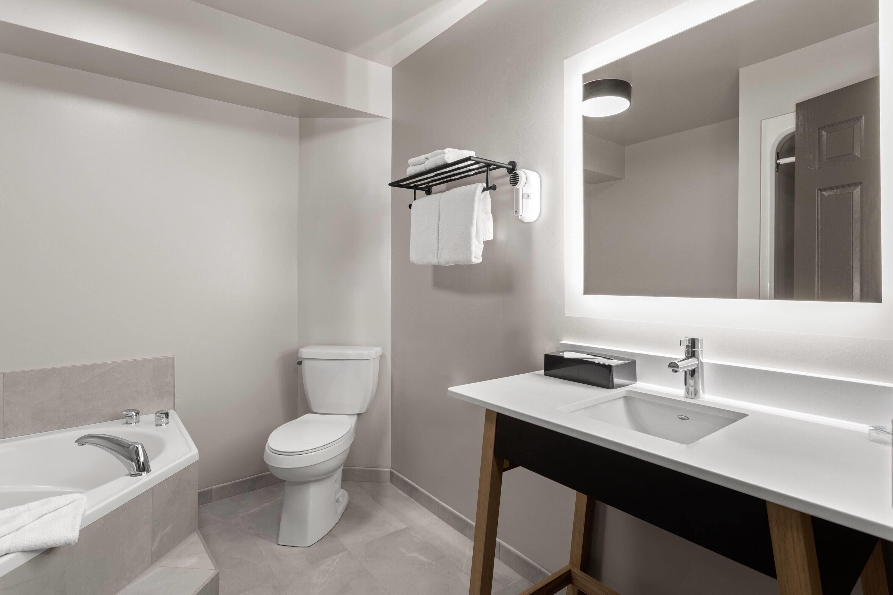 A modern bathroom with a white sink, a toilet, and a towel rack.