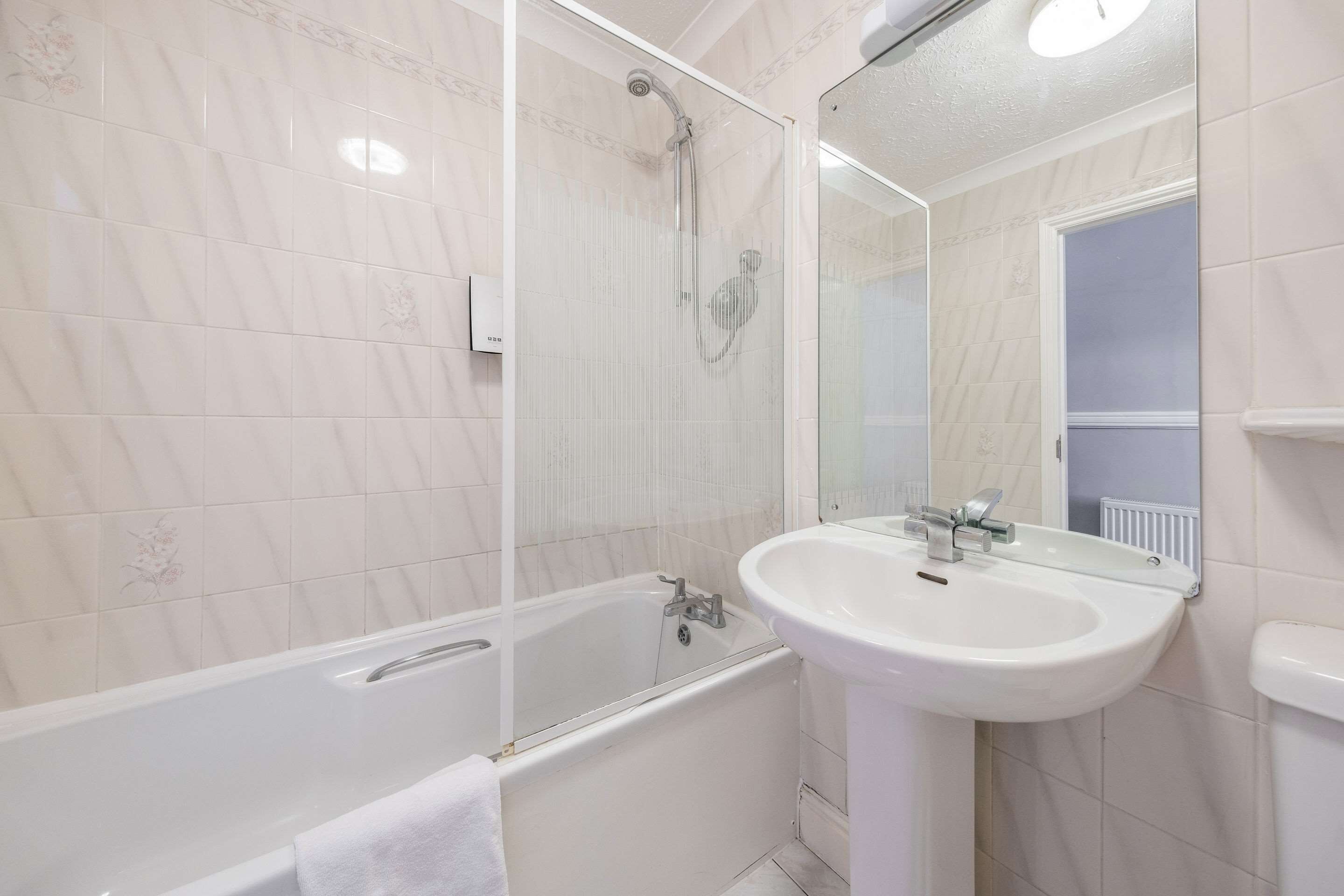 A bathroom with a bathtub, a sink, and a mirror.