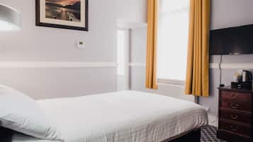 A hotel room with a bed, a dresser, a television, a picture on the wall, and a window with curtains.