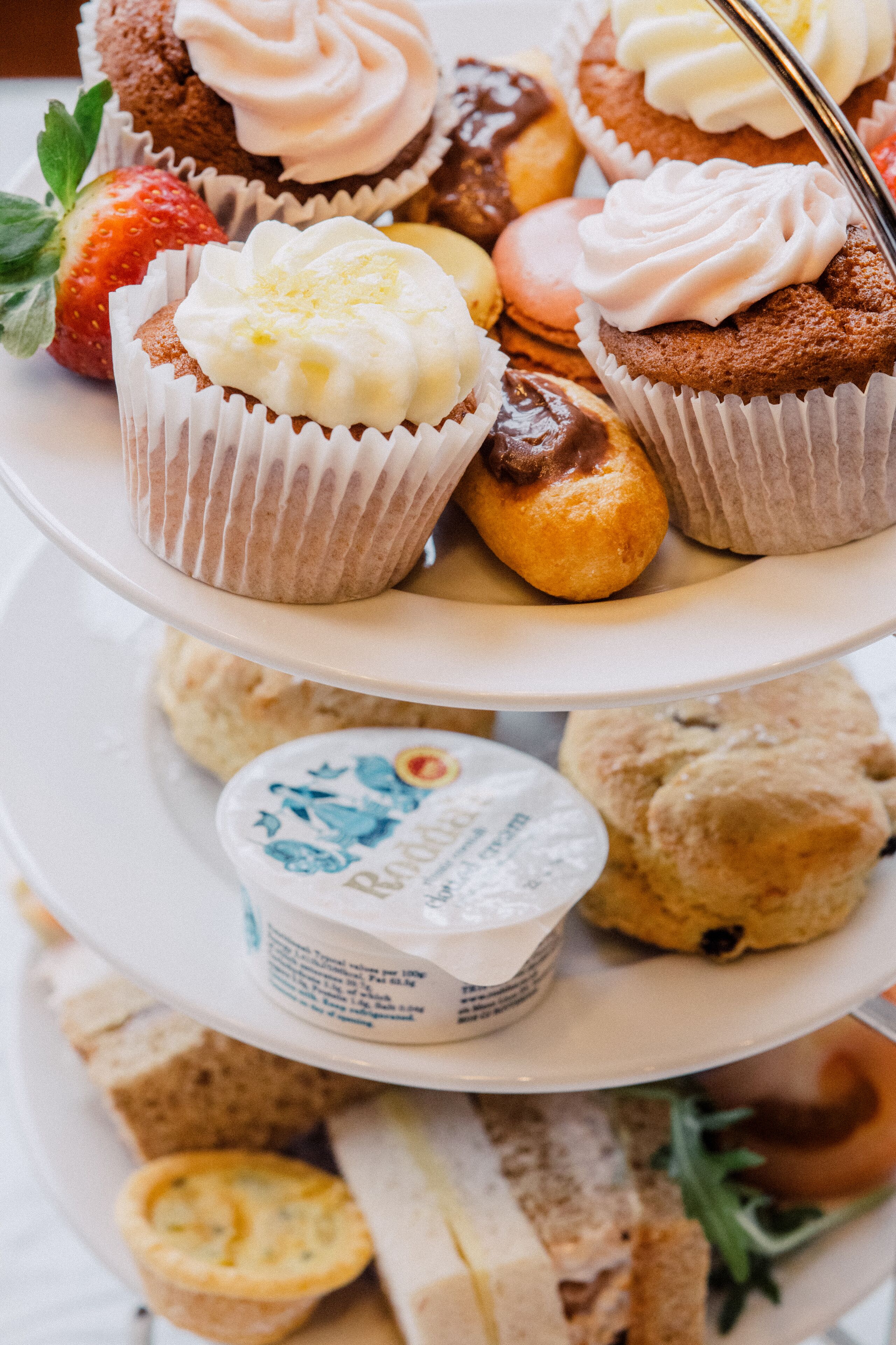 A tiered dessert platter with various pastries and a small container of yogurt.