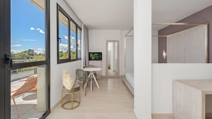 Um apartamento moderno com amplas janelas, área de jantar, TV e varanda.