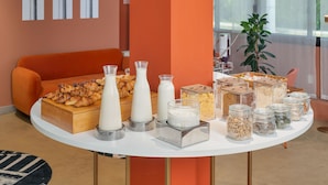 Um buffet de café da manhã com pães, leite e cereais.