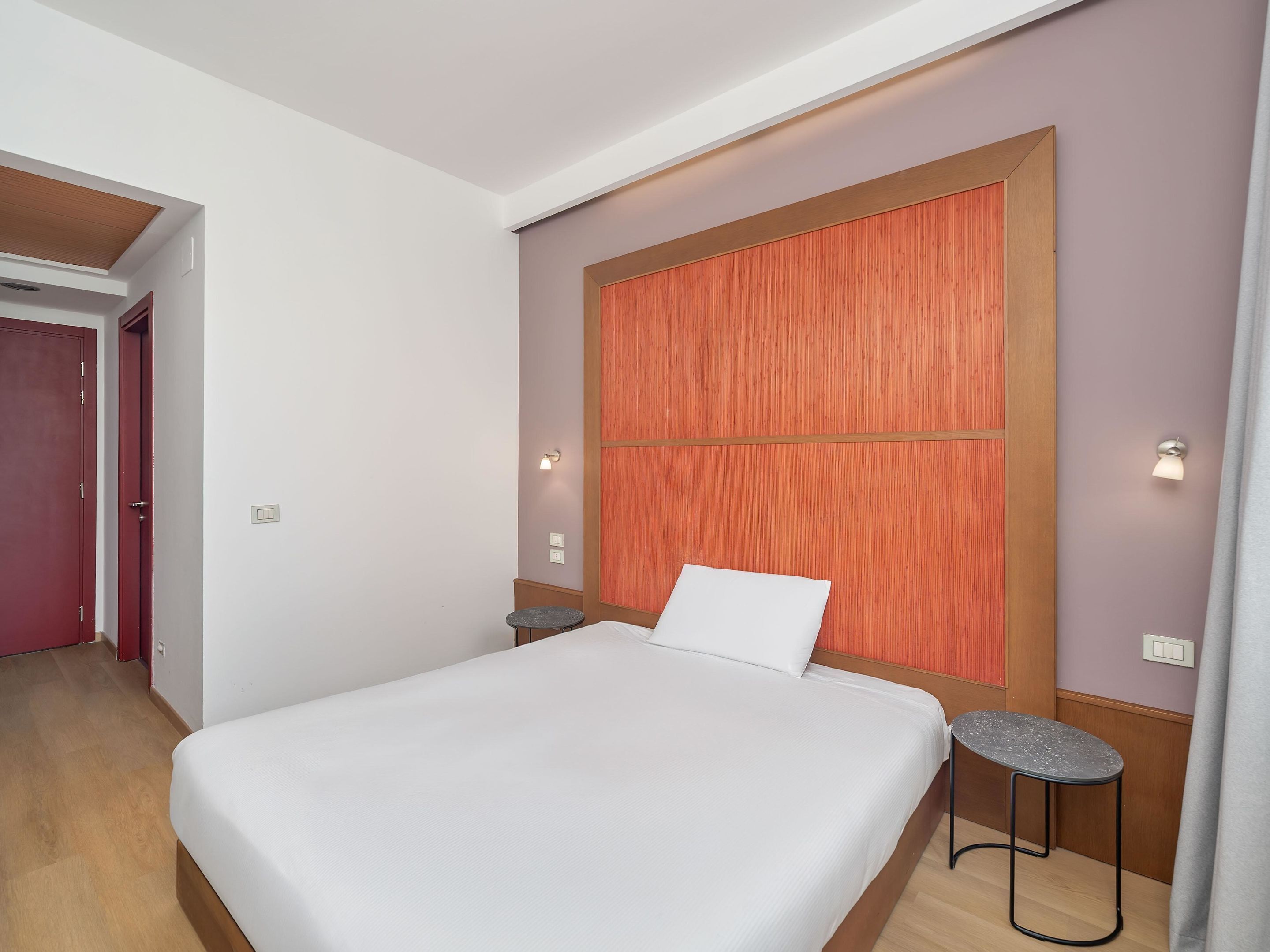 Un dormitorio con una cama grande, dos mesitas de noche, un cabecero de madera y una puerta.