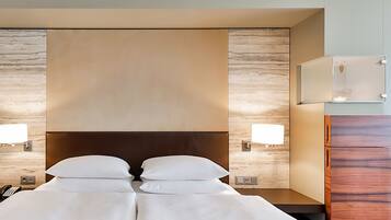 Habitación de hotel con una cama grande, dos lámparas de noche, un mesita de noche, cabecera de madera y un espejo integrado.