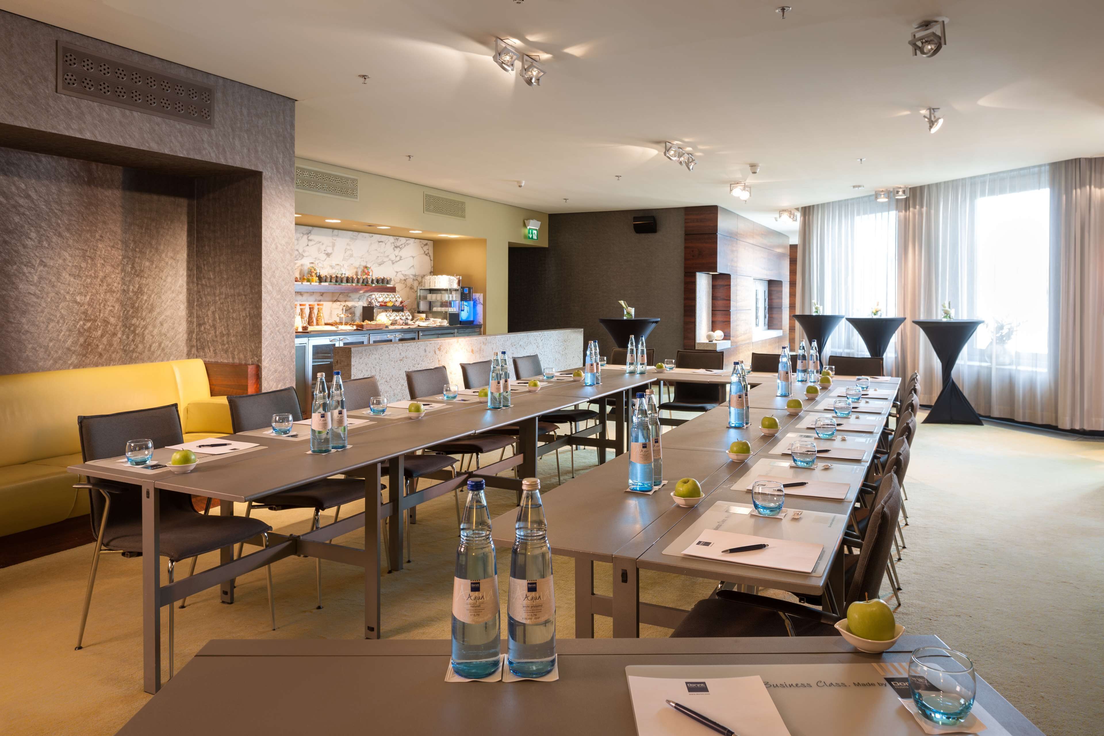 Ein Konferenzraum mit einem langen Tisch, Stühlen und einer Bar im Hintergrund.