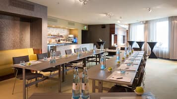 Ein Konferenzraum mit einem langen Tisch, Stühlen und einer Bar im Hintergrund.