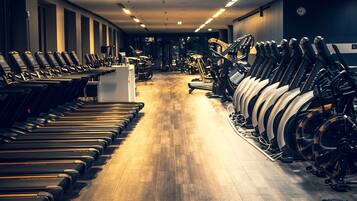 A gym with treadmills and stationary bikes lined up along the walls.
