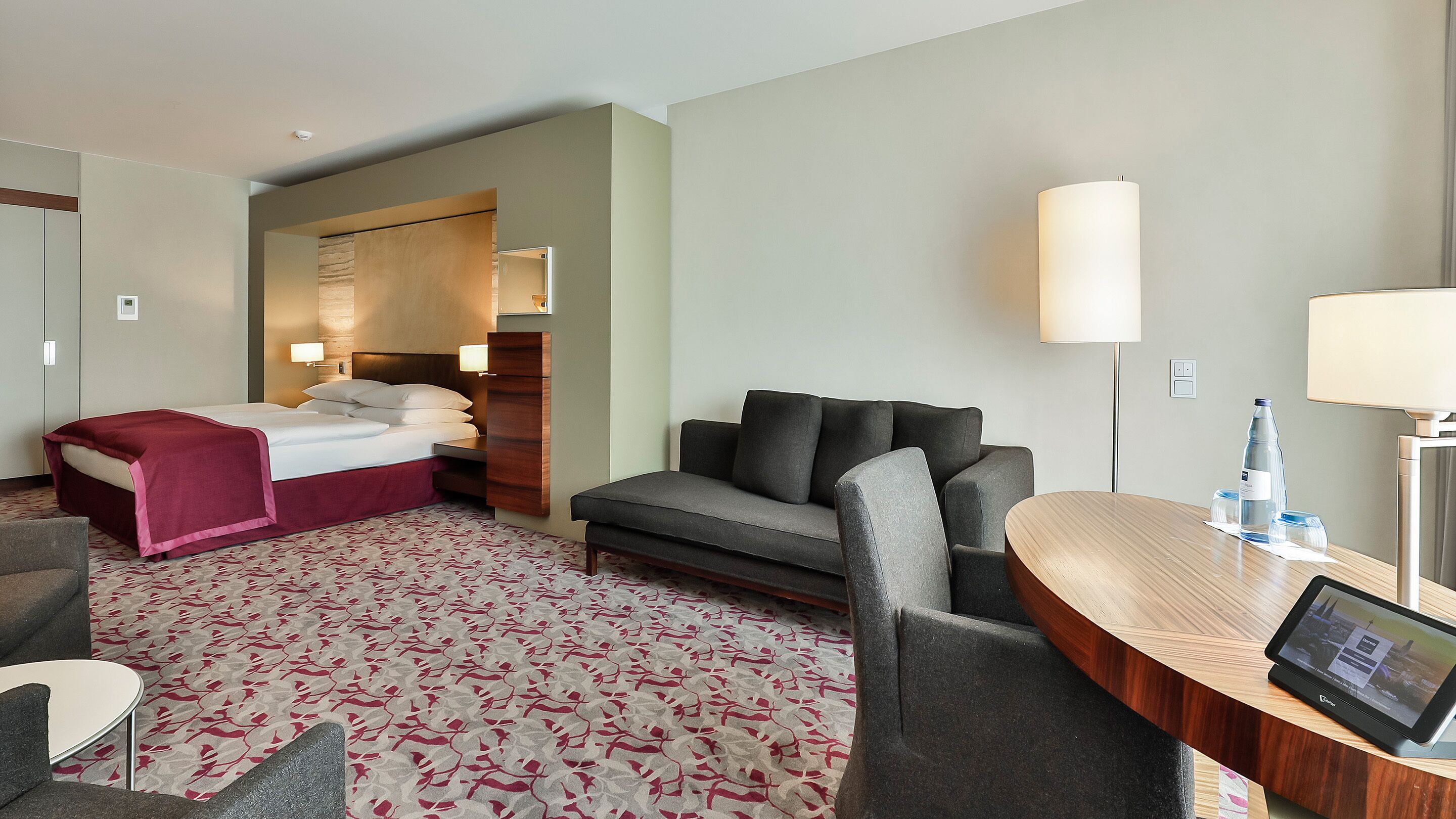 A hotel room with a bed, a sofa, a desk, and a chair.