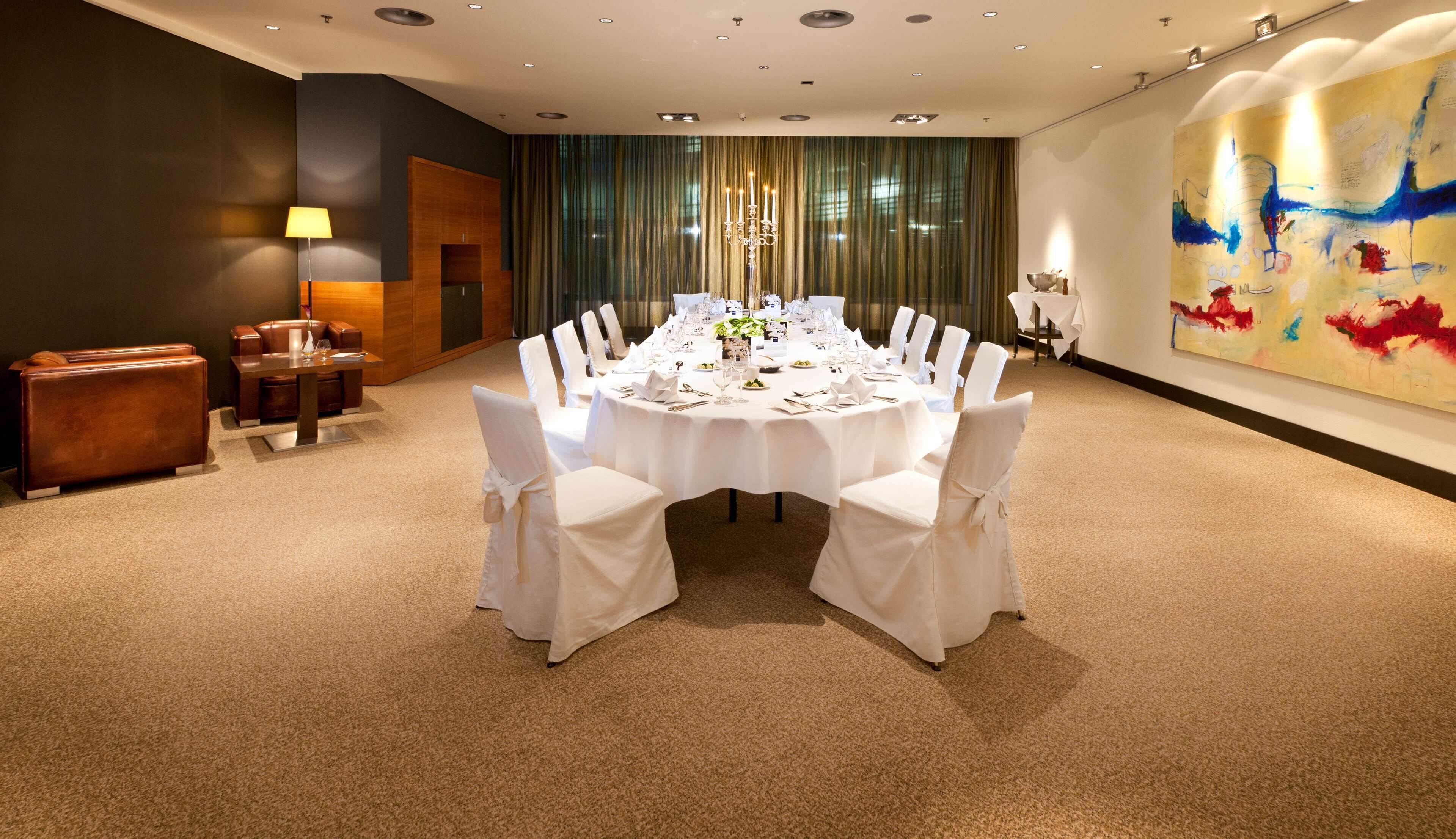A round dining table with white tablecloth and chairs, set for a formal meal.