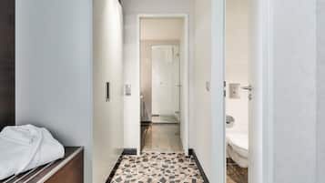 Ein Hotelkorridor mit Dusche, Toilette und einem Bett mit weißer Bettdecke.