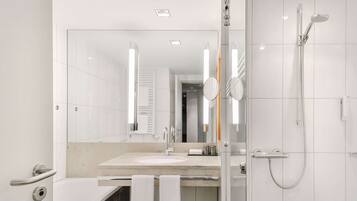 Une salle de bain moderne avec un grand miroir, un lavabo, une douche et des toilettes.