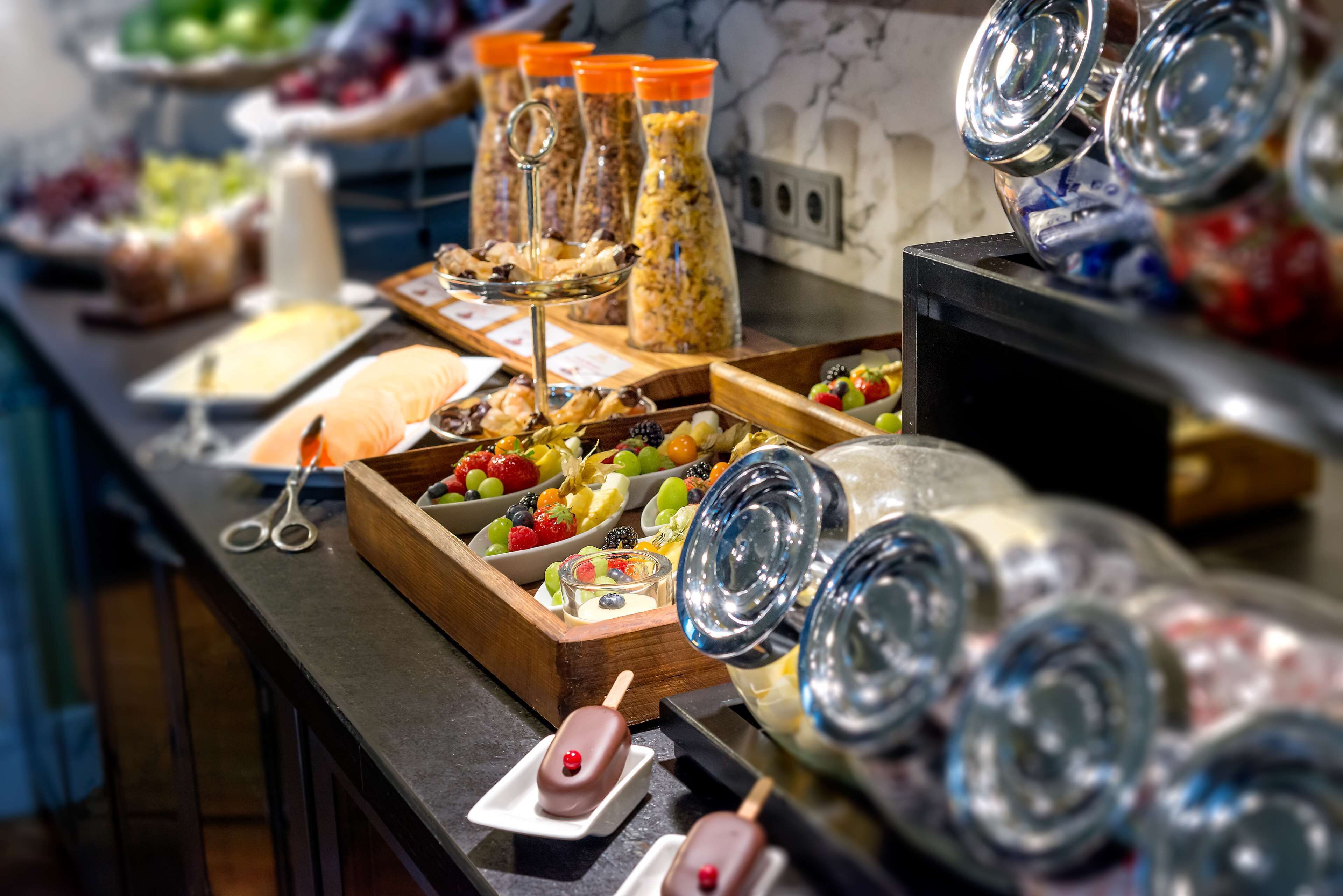 A buffet with various food items, including fruits, cheeses, and desserts.
