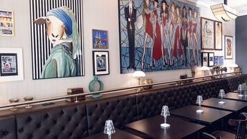 Un restaurante con una barra larga, asientos de cuero negro tipo cabina y un gran mural en la pared.