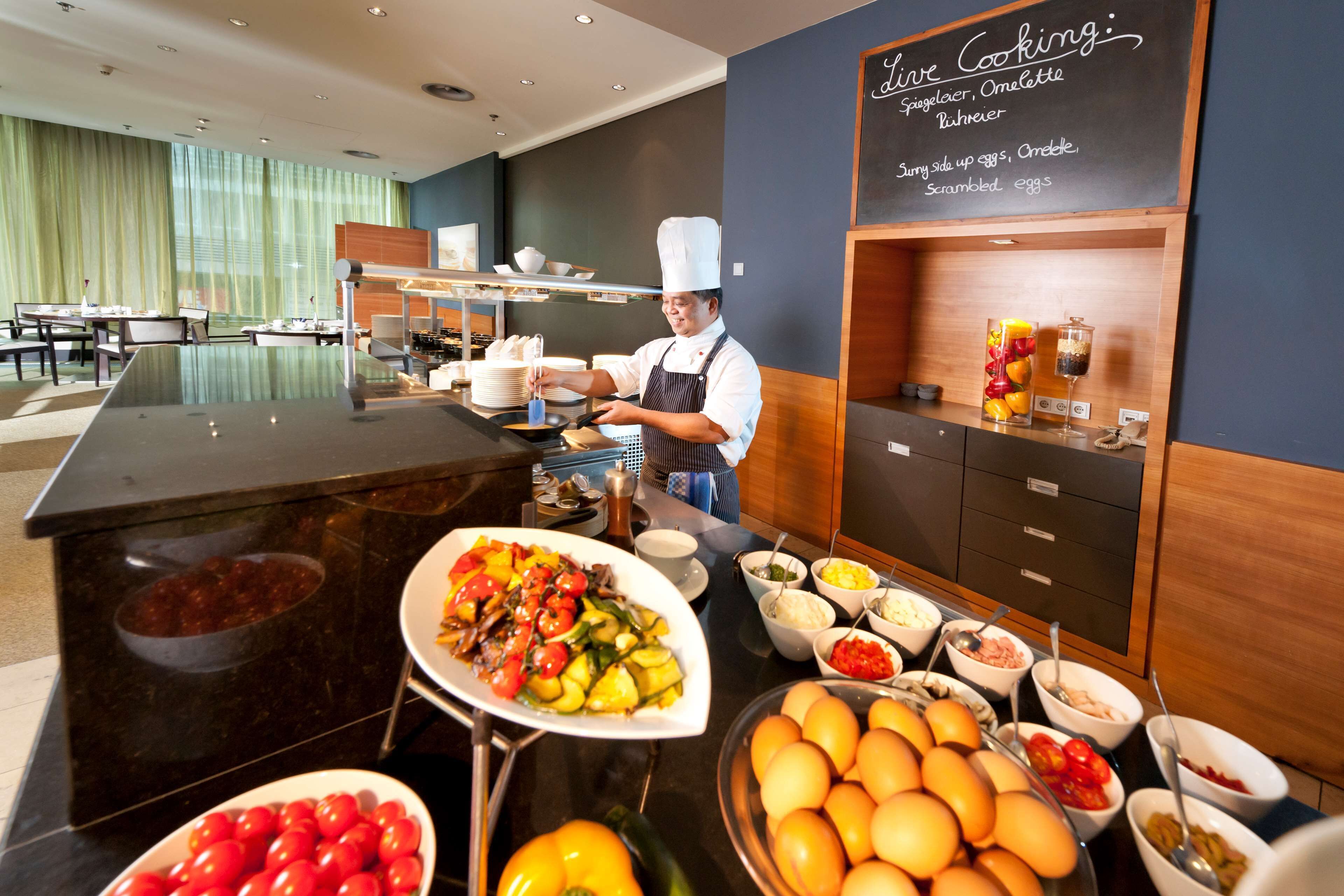 A buffet setup with a chef preparing food, a variety of dishes, and a sign indicating live cooking.